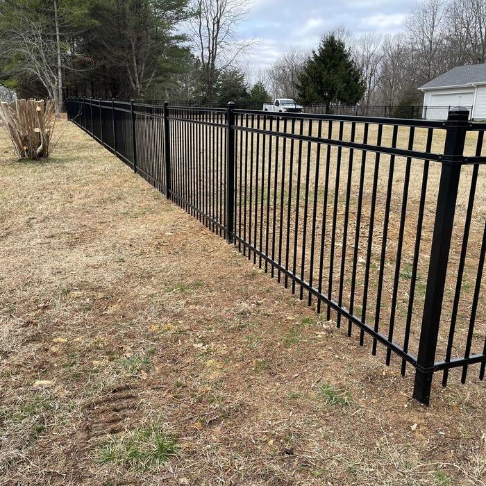 Black ornamental fence with a walk gate stretching along a residential lot line