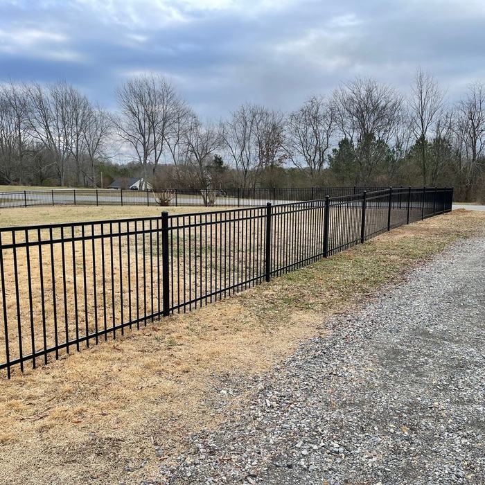 Ornamental steel fence and gate framing a gravel driveway entrance
