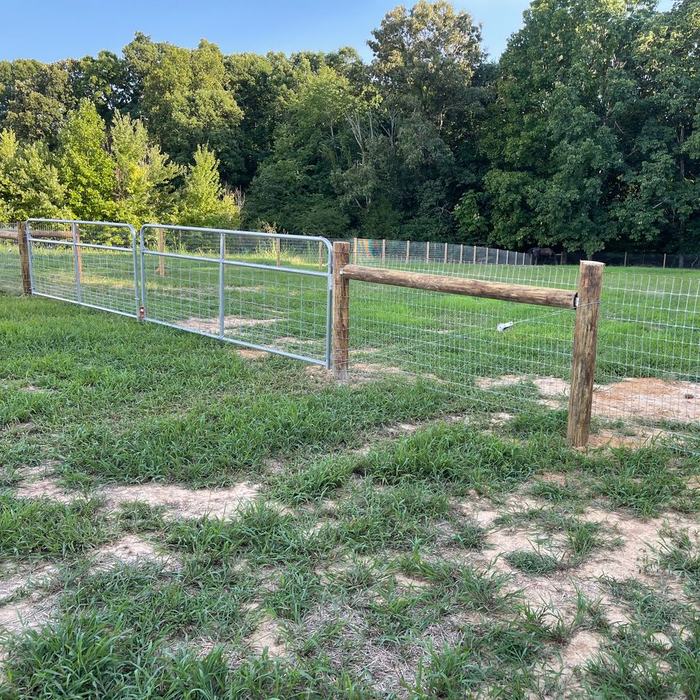 Livestock fence with a wire filled gate opening into a pasture