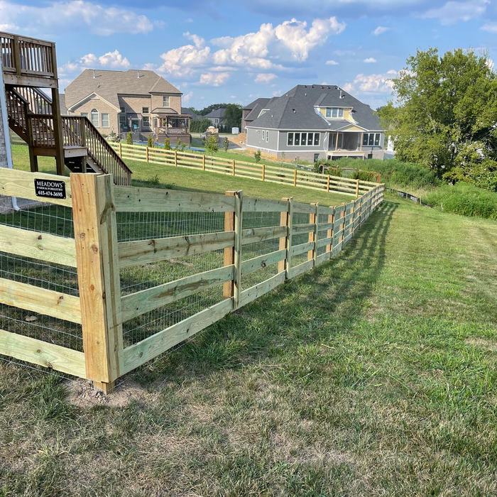 Rail fence with wire mesh backing enclosing a large residential back yard