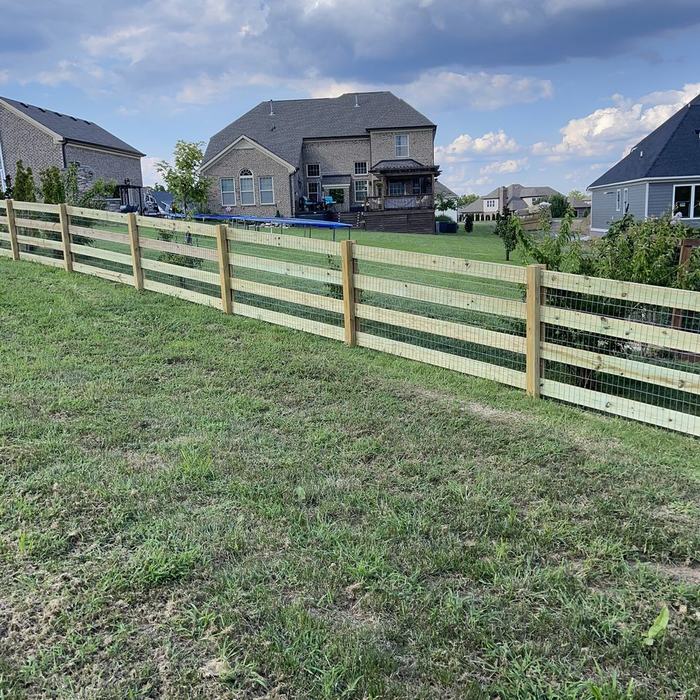 Four board rail fence marking the boundary behind a row of new homes