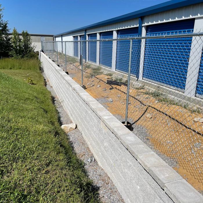 Chain link fence installed on top of a concrete retaining wall at a storage building