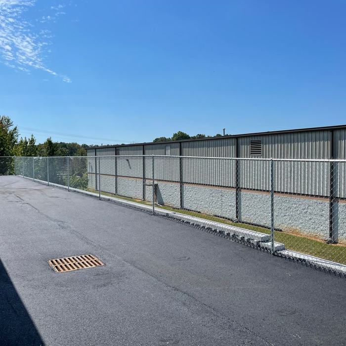 Commercial chain link fence lining the paved drive of a storage facility