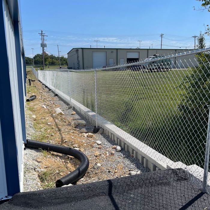 Chain link fence terminating at a blue metal building on a commercial property