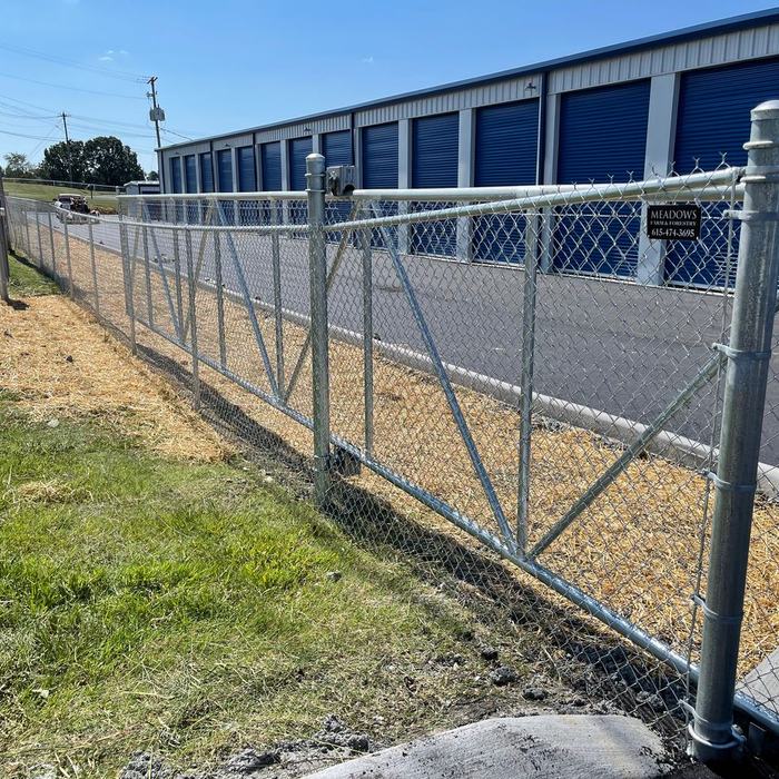 Chain link fence with a wide swing gate at the entrance of a storage facility