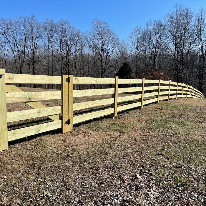 Curved four board rail fence with cross bracing along a wooded tree line
