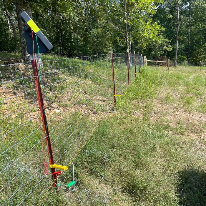 Electric fence gate handle and step in posts on a livestock wire fence